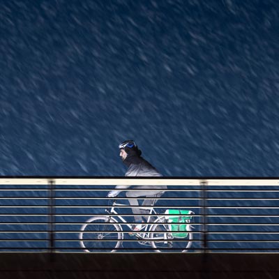 Cyklist på bro i snö och mörker